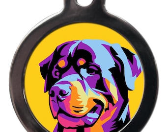 May include: A round, silver dog tag with a colorful pop art illustration of a Rottweiler dog's head on a yellow background.