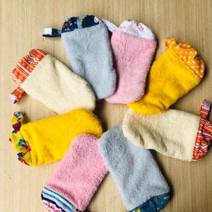 May include: Set of eight colorful oven mitts with different patterns. The mitts are made of a soft, absorbent material and have a loop for hanging.