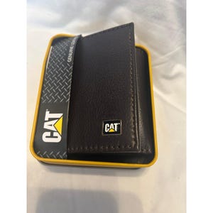 May include: A brown leather wallet with the CAT logo in a black and yellow box. The wallet is in a black and yellow box with the CAT logo and the words "GENUINE LEATHER" printed on the side.