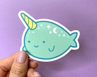 May include: A light blue narwhal sticker with a yellow horn and white stars and a crescent moon.