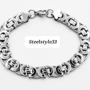 May include: A silver chain bracelet with a clasp fastening. The chain is made of interlocking links in a circular pattern.