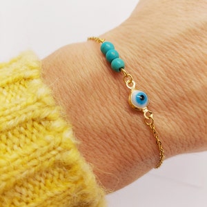 Op de afbeelding: Gouden ketting armband met een blauwe kwade oog bedel en turquoise kralen.