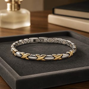 May include: A two-tone link bracelet featuring alternating silver-coloured and gold-coloured X-shaped segments. The bracelet has a polished metallic finish and a secure clasp mechanism, creating a continuous circular band of interconnected metal pieces.