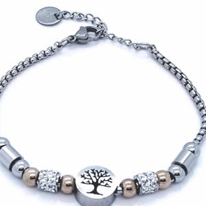 May include: A silver bracelet featuring a tree of life charm, gold beads, and clear crystal beads.