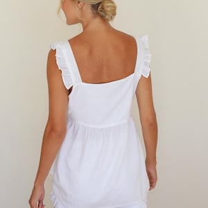 Op de afbeelding: Witte tweedelige set met een top met vierkante halslijn en brede bandjes en bijpassende shorts. De top heeft een geplooid detail in de taille. De shorts hebben een gefranjerde zoom. De outfit is gemaakt van een lichte stof.