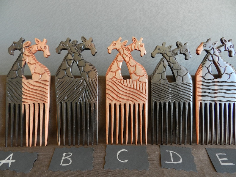 May include: Five wooden combs with giraffe designs. The combs are in different colors, including natural wood, black, and gray. The combs are labeled A through E.