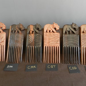 May include: Six wooden combs with carved animal figures on top. The combs are made of dark wood and have a natural finish. The animal figures are all different and include a hippopotamus, a tiger, and a bear. The combs are labeled with the letters BNE, BHA, CMR, CQT, COD, and CDA.