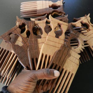 Puede incluir: Una colecci&oacute;n de peines de madera con dise&ntilde;o de dientes anchos y un mango decorativo con un recorte central. Los peines est&aacute;n hechos de madera de dos tonos, mostrando patrones de grano contrastantes en marr&oacute;n claro y oscuro.
