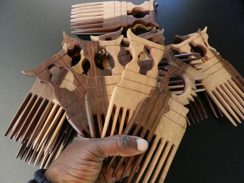 Puede incluir: Una colecci&oacute;n de peines de madera con dise&ntilde;o de dientes anchos y un mango decorativo con un recorte central. Los peines est&aacute;n hechos de madera de dos tonos, mostrando patrones de grano contrastantes en marr&oacute;n claro y oscuro.