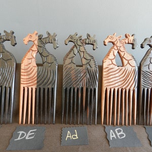 May include: Five wooden combs with giraffe head handles. The combs are in different shades of brown and black. The combs are labeled with letters: AC, DE, AD, AB, and G.
