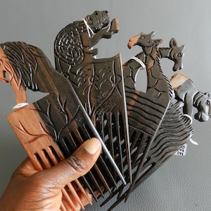 May include: Set of five wooden combs with animal carvings. The combs are black and brown with intricate details. The animals include a lion, a giraffe, a zebra, a hippopotamus, and a turtle.