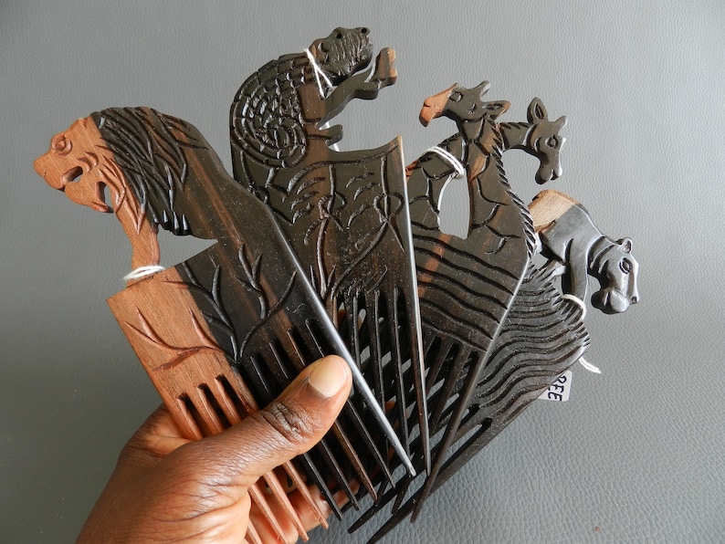 May include: Set of five wooden combs with animal carvings. The combs are black and brown with intricate details. The animals include a lion, a giraffe, a zebra, a hippopotamus, and a turtle.