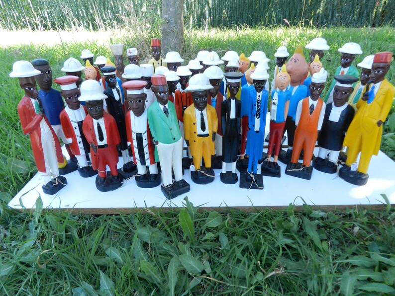 Puede incluir: Una colecci&oacute;n de numerosas figuras de madera pintadas a mano que representan a individuos con diversos atuendos profesionales, incluyendo trajes, sombreros y uniformes en colores vibrantes como rojo, amarillo, azul, verde y negro, sobre una tabla blanca.