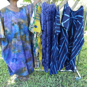 Peut inclure: Quatre kaftans de différentes couleurs bleu et brun, suspendus à un portant. Les kaftans sont faits d'un tissu doux et fluide et ont une coupe ample.