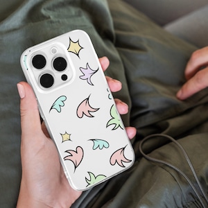 Puede incluir: Una funda transparente para teléfono con fondo blanco y un patrón colorido de estrellas, hojas y remolinos. La funda está diseñada para un teléfono con una cámara de triple lente.