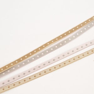 May include: Four different types of ribbon with a dotted pattern. The ribbons are beige, light pink, gray, and a darker beige.