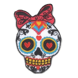Peut inclure: Patch brodé représentant un crâne de sucre coloré avec un nœud rouge, des contours noirs et des cœurs pour les yeux.