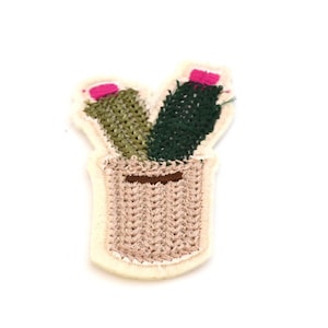 Può includere: Una pianta di cactus ricamata in verde e marrone in un vaso beige con fiori rosa. La toppa è perfetta per aggiungere un tocco di fantasia a vestiti, borse o altri oggetti artigianali.