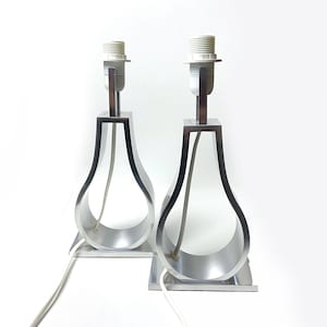 Op de afbeelding: Een paar zilveren tafellampen met een uniek peer-vormig ontwerp. De lampen hebben een eenvoudige, moderne esthetiek en zouden een geweldige aanvulling zijn op elk huis.