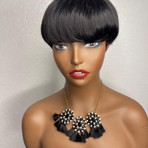 May include: A black wig with a short, blunt bob style. The wig is styled with a fringe and has a natural, sleek finish.