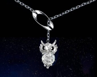 May include: A silver-toned owl pendant necklace. The owl pendant is encrusted with clear crystals, and hangs from a delicate chain. The necklace features a unique oval-shaped clasp. The background is a dark gradient with a starry effect.