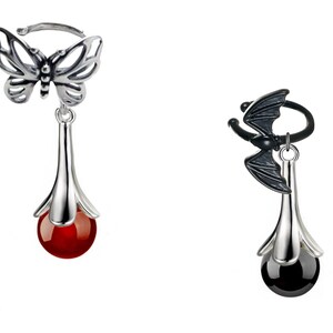 May include: Two silver dangle earrings with a red and black gemstone. The top of each earring features a silver butterfly and bat charm.