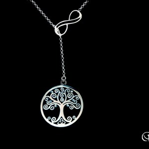May include: A silver necklace with an infinity symbol and a tree of life pendant with clear crystals. The pendant is round and has a detailed design.