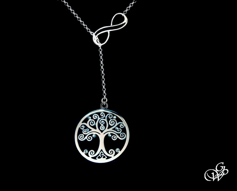 May include: A silver necklace with an infinity symbol and a tree of life pendant with clear crystals. The pendant is round and has a detailed design.