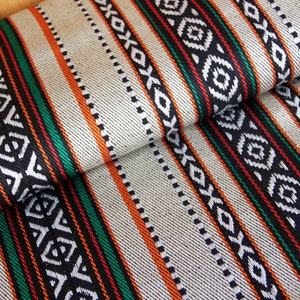 Peut inclure: Gros plan sur un tissu blanc à rayures noires, orange et vertes. Le tissu présente un motif tissé avec des motifs géométriques.