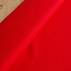 May include: A close-up of a bright red fabric, folded in half, showing the smooth texture of the material.