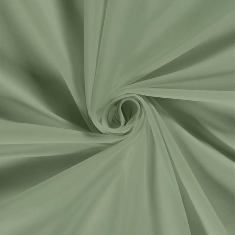Pu&ograve; includere: Primo piano di un tessuto verde salvia, disposto a spirale. Il tessuto ha una consistenza morbida e fluida, con sottili variazioni di tono che creano profondit&agrave;. Le pieghe e le curve del materiale sono evidenziate dalla luce.
