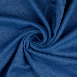 May include: Close-up of a swirl of deep blue fabric. The material appears soft and has a subtle texture, with folds and shadows creating depth. The color is a rich, solid blue.