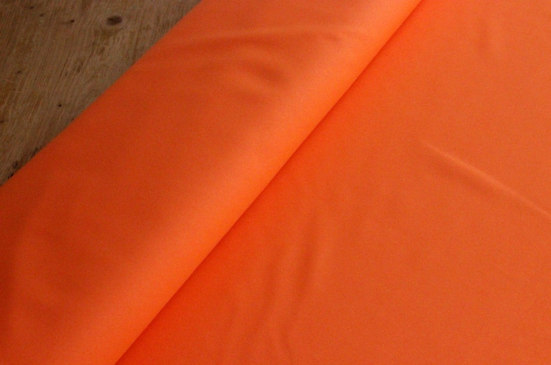 May include: A bright orange fabric, folded in half, with a smooth texture.