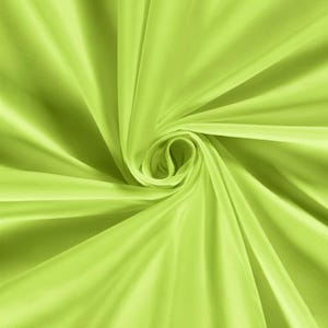Pu&ograve; includere: Primo piano di un tessuto verde lime vibrante. Il materiale &egrave; liscio e fluido, con morbide pieghe e un motivo a vortice che crea un senso di movimento. Il tessuto sembra leggero, forse seta o raso.