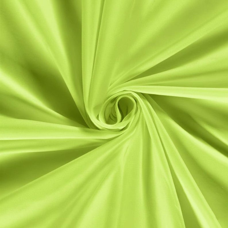 Pu&ograve; includere: Primo piano di un tessuto verde lime vibrante. Il materiale &egrave; liscio e fluido, con morbide pieghe e un motivo a vortice che crea un senso di movimento. Il tessuto sembra leggero, forse seta o raso.