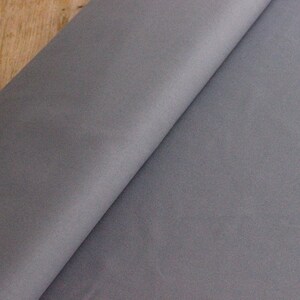 May include: A close-up of a piece of gray fabric. The fabric has a smooth, slightly textured surface.