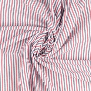 Puede incluir: Tela blanca con rayas rojas y azules. La tela est&aacute; doblada y retorcida, creando un patr&oacute;n de remolino.