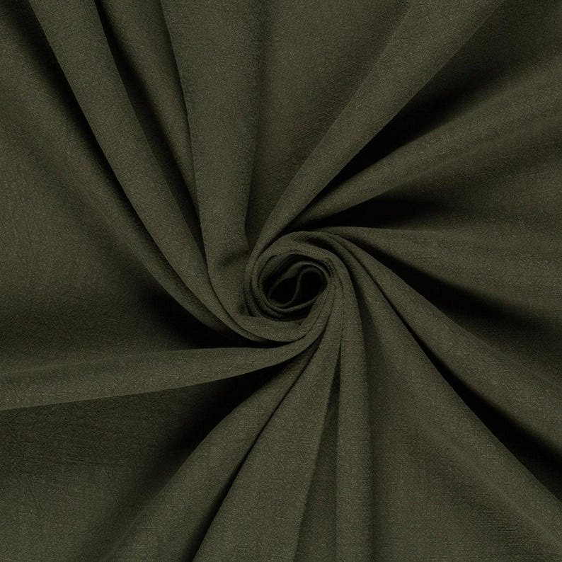 May include: Close-up of olive green fabric with a soft, textured appearance. The fabric is arranged in a spiral, creating a swirling pattern. The color is a deep, earthy tone, suitable for various textile projects.
