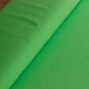 May include: A roll of bright green fabric. The fabric is smooth and has a slight sheen.