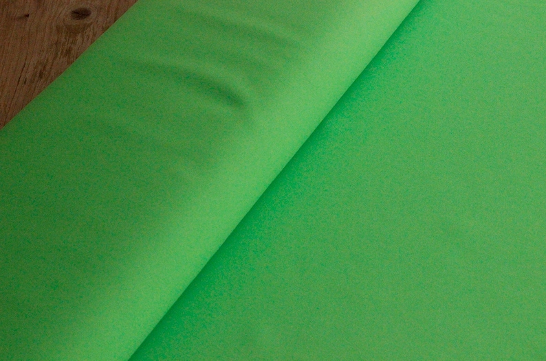 May include: A roll of bright green fabric. The fabric is smooth and has a slight sheen.