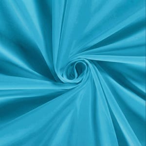 Pu&ograve; includere: Primo piano di un tessuto turchese vibrante con una lucentezza serica. Il tessuto &egrave; artisticamente drappeggiato e arricciato, creando un motivo dinamico di luci e ombre. Le pieghe e le curve del materiale aggiungono profondit&agrave; e consistenza all'immagine.