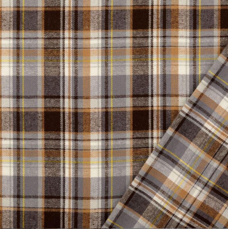 May include: Close-up of a plaid fabric in shades of brown, gray, white, and yellow. The pattern features intersecting lines creating a grid-like design. The fabric is folded over, revealing the reverse side with a similar pattern.