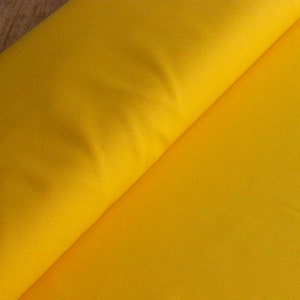 May include: A bright yellow fabric, folded in half, with a smooth texture.