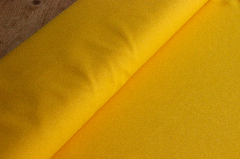 May include: A bright yellow fabric, folded in half, with a smooth texture.