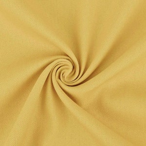 May include: A close-up of a yellow fabric with a textured surface. The fabric is folded and twisted, creating a spiral pattern.