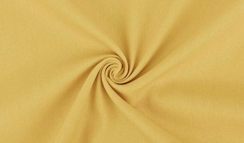 May include: A close-up of a yellow fabric with a textured surface. The fabric is folded and twisted, creating a spiral pattern.