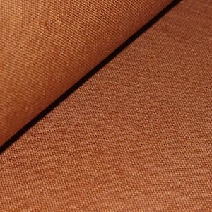 Könnte beinhalten: Nahaufnahme eines braunen Stoffes mit einer strukturierten Webart. Der Stoff hat einen dezenten Glanz und ein leicht raues Gefühl.