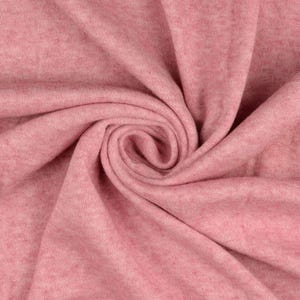 May include: Close-up of a swirl of soft, pink fabric. The material has a subtle texture and a heathered appearance, with variations in the pink hue. The fabric is tightly folded, creating a spiral pattern.
