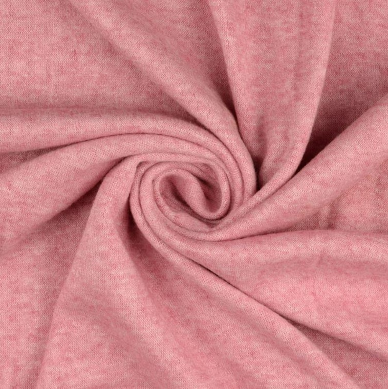 May include: Close-up of a swirl of soft, pink fabric. The material has a subtle texture and a heathered appearance, with variations in the pink hue. The fabric is tightly folded, creating a spiral pattern.