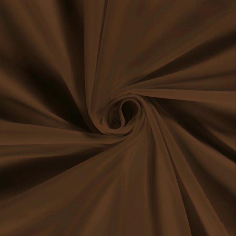 Pu&ograve; includere: Primo piano di tessuto marrone disposto a spirale, con pieghe morbide e una texture fluida. Il materiale sembra leggero, forse seta o un tessuto delicato simile. Il colore &egrave; un marrone ricco e caldo, con variazioni di tonalit&agrave;.